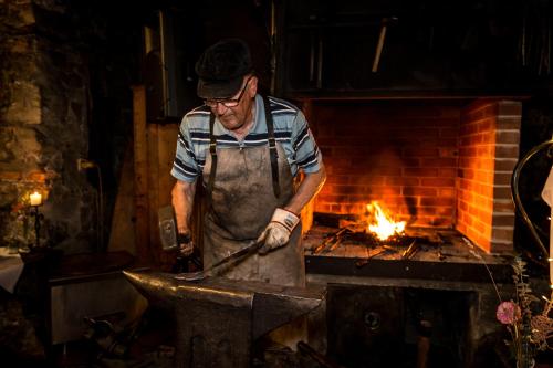 a man in an apron cooking on a iron grill at Naturidyll Hotel Hammerschmiede in Anthering