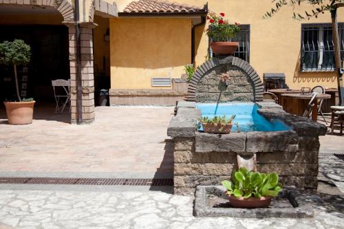 a stone fountain in a courtyard with potted plants at Albergo Da Benedetta in Vetralla