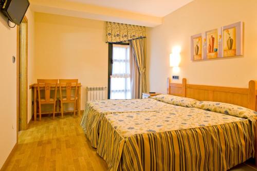 
a bedroom with a bed and a dresser at Hotel Restaurante La Casilla in Cangas del Narcea
