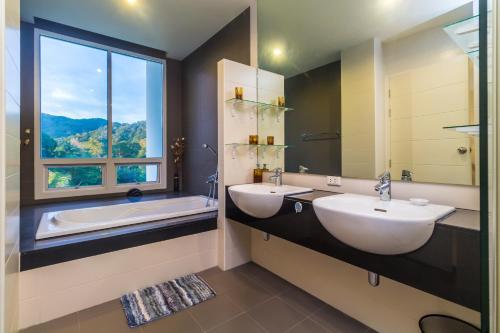 a bathroom with two sinks and a tub and a window at The Palm at Veloche Group by Lofty in Karon Beach