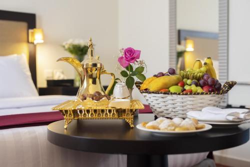 a table with a basket of fruit and a tea kettle at Al Joud Hotel Makkah in Makkah