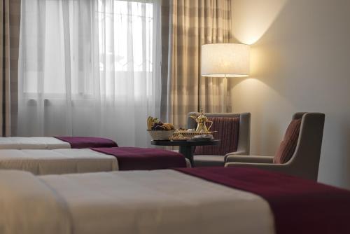 a room with four beds and a table and a lamp at Al Joud Hotel Makkah in Makkah