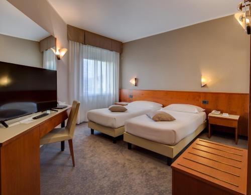 a hotel room with two beds and a flat screen tv at Best Western Hotel Turismo in San Martino Buon Albergo