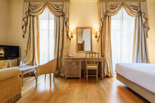 a room with a bed, table, chairs and a lamp at Hotel Real Palacio in Lisbon