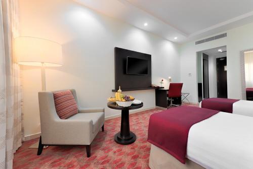 a hotel room with a bed and a chair and a television at Al Joud Hotel Makkah in Makkah