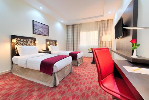 a hotel room with two beds and a desk at Al Joud Hotel Makkah in Makkah