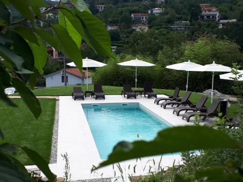 a swimming pool with lounge chairs and umbrellas at Guest House Stancija Kovacici in Opatija