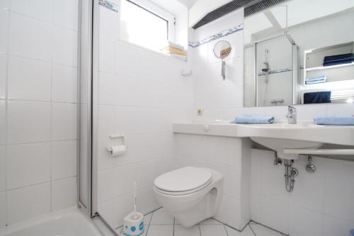 a white bathroom with a toilet and a sink at Apartments Benser-Hof in Bensersiel