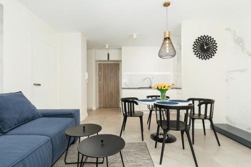 里沃的住宿－Apartament Klifowa z widokiem na morze i basenem，客厅配有蓝色的沙发、桌子和椅子
