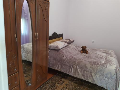 un osito de peluche sentado en una cama junto a un espejo en Armine B&B, en Tatʼev
