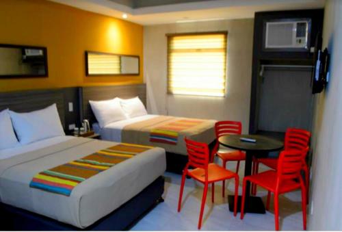 Habitación de hotel con 2 camas, mesa y sillas en Express Inn Cebu Osmena, en Cebú