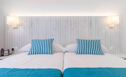 a bedroom with two beds with blue and white pillows at BLUESEA Gran Playa in Sa Coma
