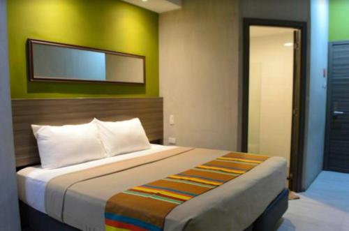 1 dormitorio con 1 cama grande y pared verde en Express Inn Cebu Osmena, en Cebú