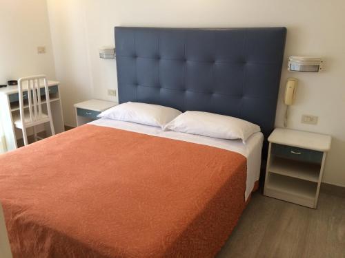 una camera da letto con un letto grande con testiera blu di Hotel Pigalle a Riccione