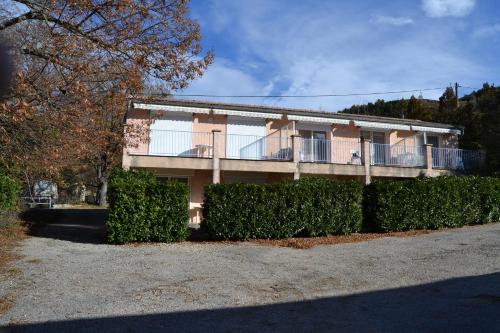 a building with a balcony and bushes in front of it at Résidence de l'Escoulaou in Castellane