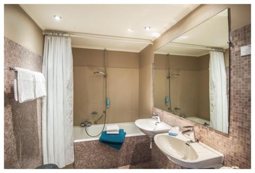 een badkamer met 2 wastafels, een bad en een spiegel bij Hotel Ter Streep in Oostende