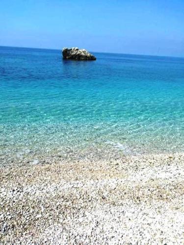 a rocky beach with a rock in the water at Rexhos Studios in Himare