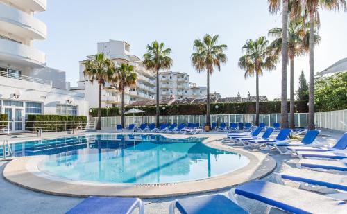 a swimming pool with lounge chairs and palm trees at BLUESEA Gran Playa in Sa Coma