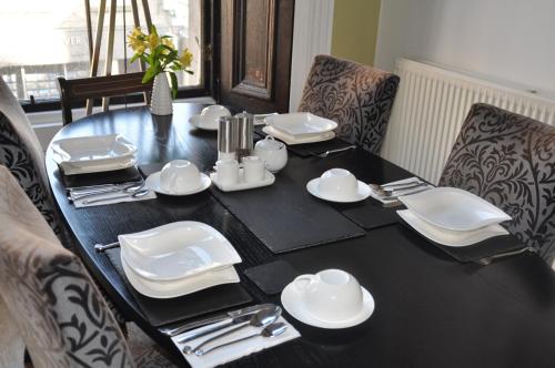 una mesa negra con platos blancos y cubiertos en The Bank Guest House, en Hawick