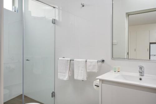 a white bathroom with a shower and a sink at Gundagai Tourist Suites in Gundagai