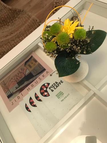 a vase of flowers on a table with a magazine at Budyně Apartment in Budyně nad Ohří