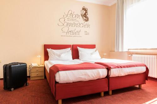 a bedroom with a red bed and a suitcase at Hotel Elisabetha Garni in Hannover