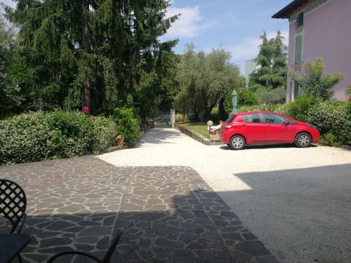 une voiture rouge garée dans une allée à côté d'une maison dans l'établissement Appartamento Villa Margherita, à Desenzano del Garda
