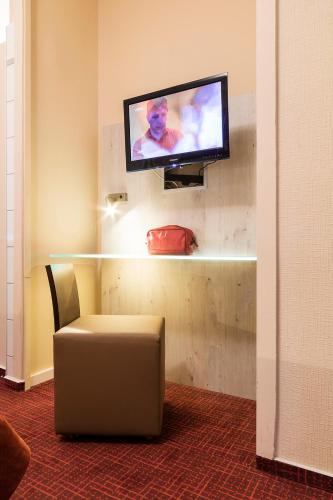 a room with a tv on a wall with a chair at Hotel Elisabetha Garni in Hannover