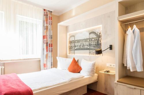 a bedroom with a bed with white sheets and orange pillows at Hotel Elisabetha Garni in Hannover