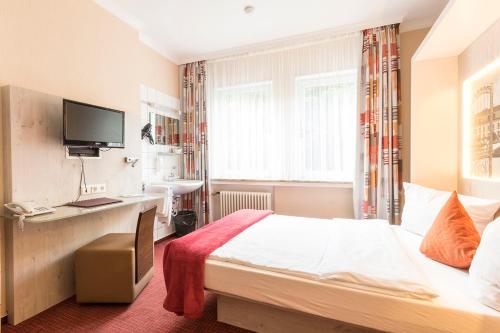 a hotel room with a bed and a desk at Hotel Elisabetha Garni in Hannover