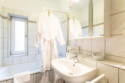 La salle de bains blanche est pourvue d'un lavabo et d'un miroir. dans l'établissement Hotel Elisabetha Garni, à Hanovre