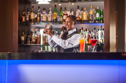 a man standing behind a bar holding a drink at Coastlands Musgrave Hotel in Durban