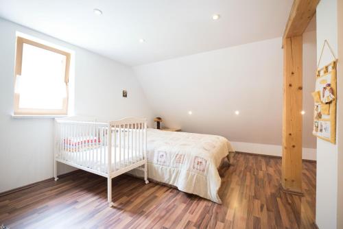 a white crib in a bedroom with a wooden floor at Yellow house in Trenta