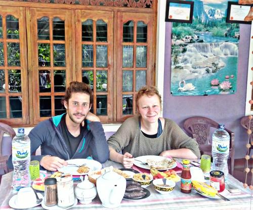 two men sitting at a table eating food at Cozy Homestay Waterfall Road Ella in Ella