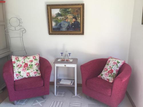 two chairs and a table with a picture on the wall at Le chant des oiseaux in Viry