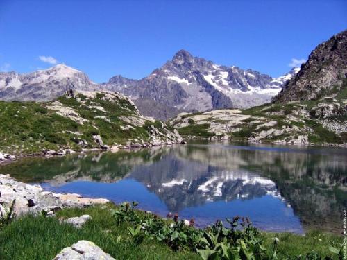 a mountain lake with snow capped mountains in the background at Chambres d'hotes Les Clarines in Saint-Jacques-en-Valgodemard