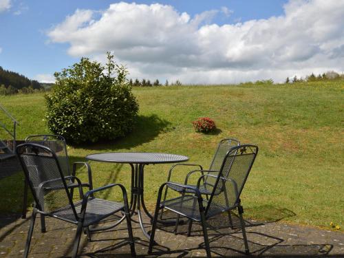 un tavolo e sedie con un campo sullo sfondo di Cosy holidayhome near the forest a Zendscheid