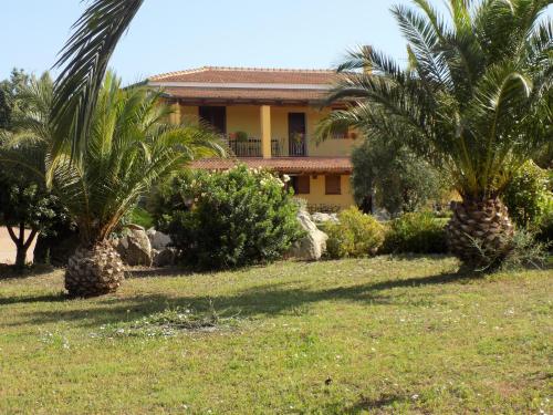 a house with two palm trees in a yard at Villa Sorrentina in Alghero