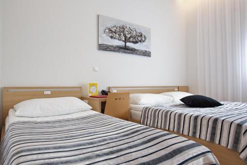 a bedroom with two beds and a tree on the wall at Dream Hotel in Velika Gorica