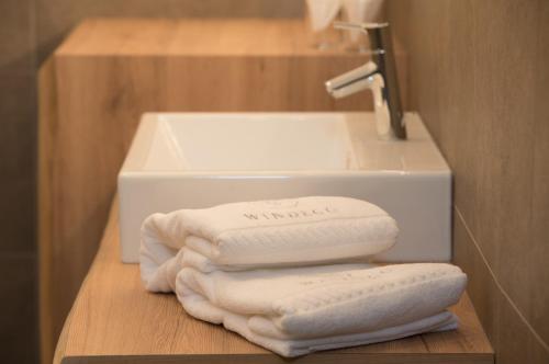 a pile of towels on a shelf next to a sink at Apartments Windegg in Caldaro