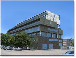 a tall building with cars parked in a parking lot at Hotel Lux in Modena