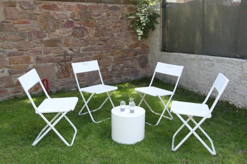 three white chairs and a table in the grass at Subtil insolite in Colmar