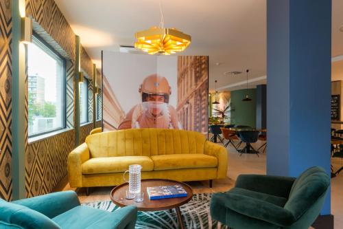 a living room with a yellow couch and a helmet on the wall at The James Rotterdam in Rotterdam