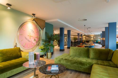 a room with green couches and a large clock on the wall at The James Rotterdam in Rotterdam