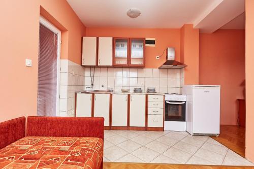 a kitchen with orange walls and white cabinets at Apartman Jovana Sokobanja in Soko Banja