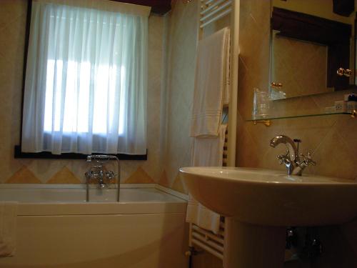 a bathroom with a sink and a toilet and a window at Hotel Cà Fiore in Bardonecchia