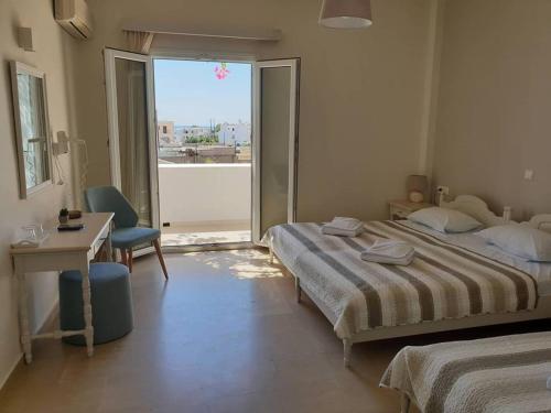 1 dormitorio con 2 camas, escritorio y ventana en Alkyon Hotel, en Kamari