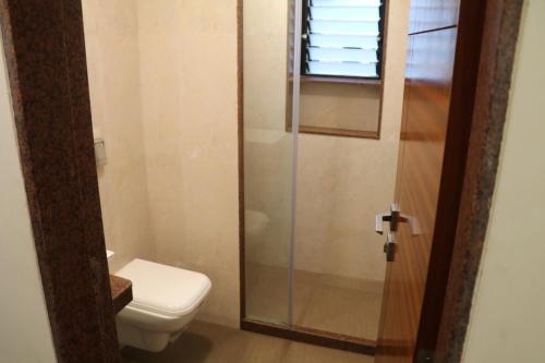 a bathroom with a toilet and a glass shower at Hotel Milan International in Mumbai
