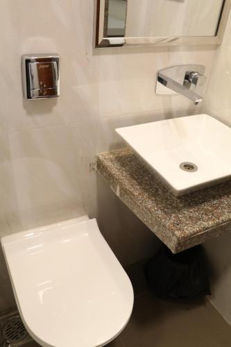 a bathroom with a white toilet and a sink at Hotel Milan International in Mumbai