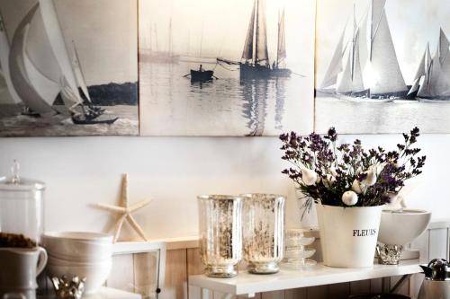 a shelf with a vase of flowers and pictures of boats at Fisher House in Sopot